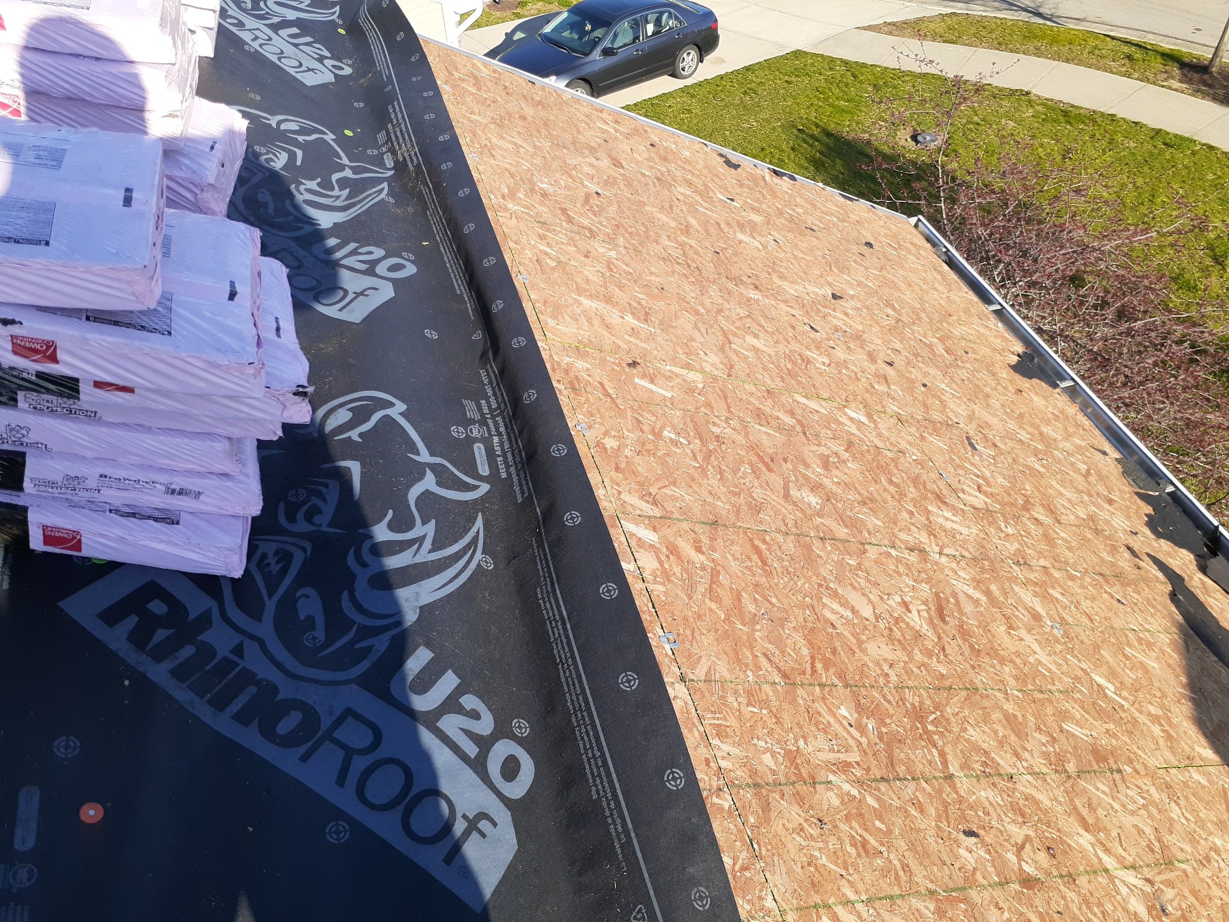 A stack of shingle bundles on RhinoRoof underlayment beside the clean deck, Xenia, Ohio.
