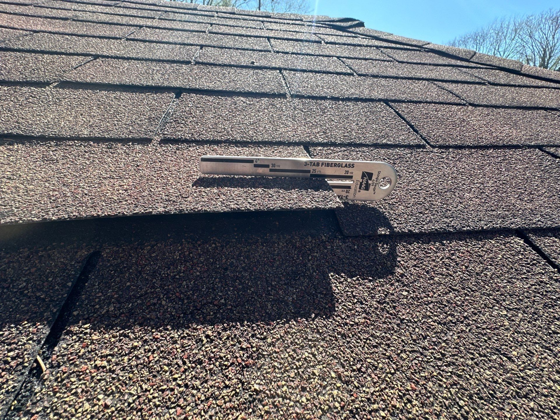 Shingle measuring tool laid on the worn granules near the ridge, Beavercreek, Ohio.