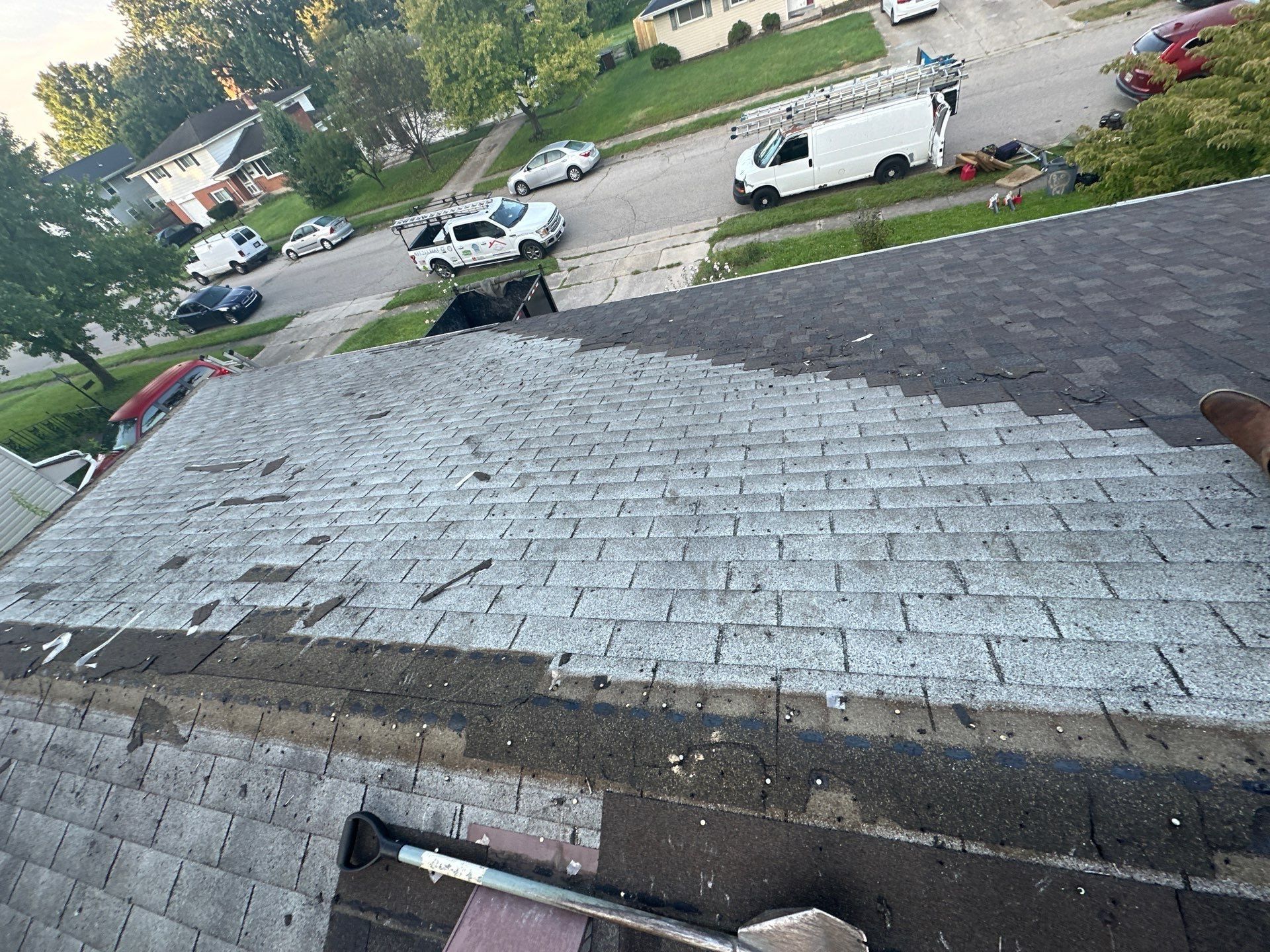 Two layers of old shingles showing where tear-off has started, above the street, Fairborn, Ohio.