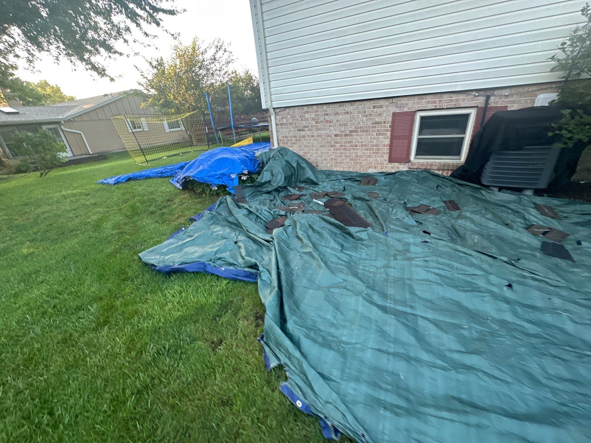 Green and blue tarps along the back wall, already catching roof debris, Dayton, Ohio.
