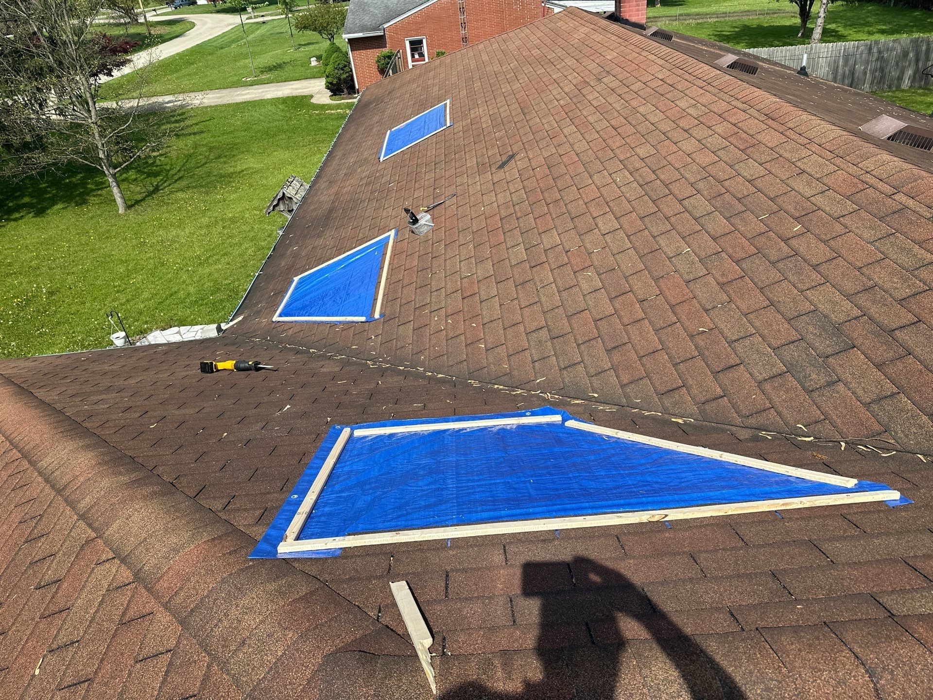 Three blue emergency tarps battened down across the damaged slopes, Beavercreek, Ohio.