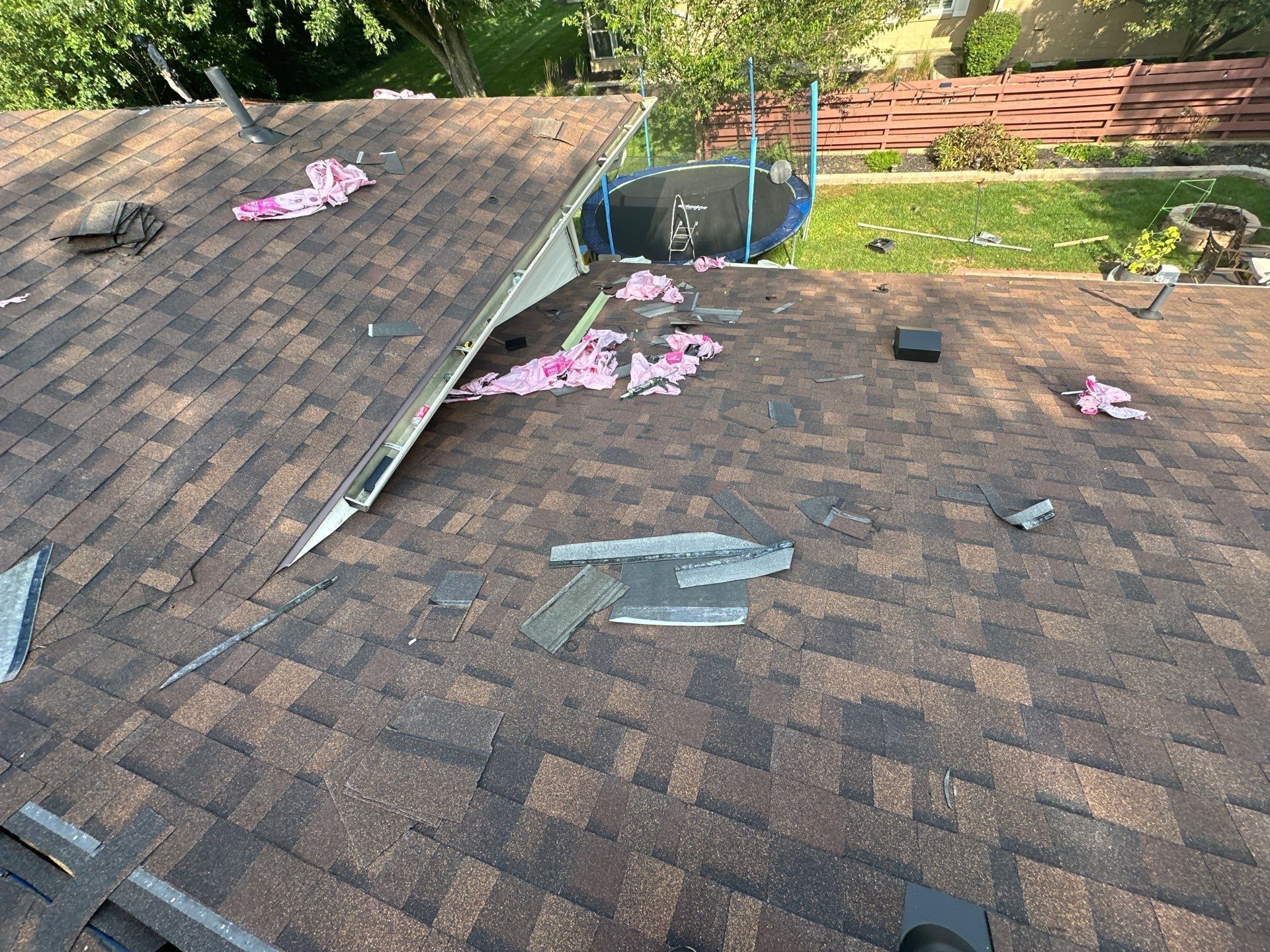 Shingles going on the lower roof below the upper roof's edge, with the trampoline below, Dayton, Ohio.