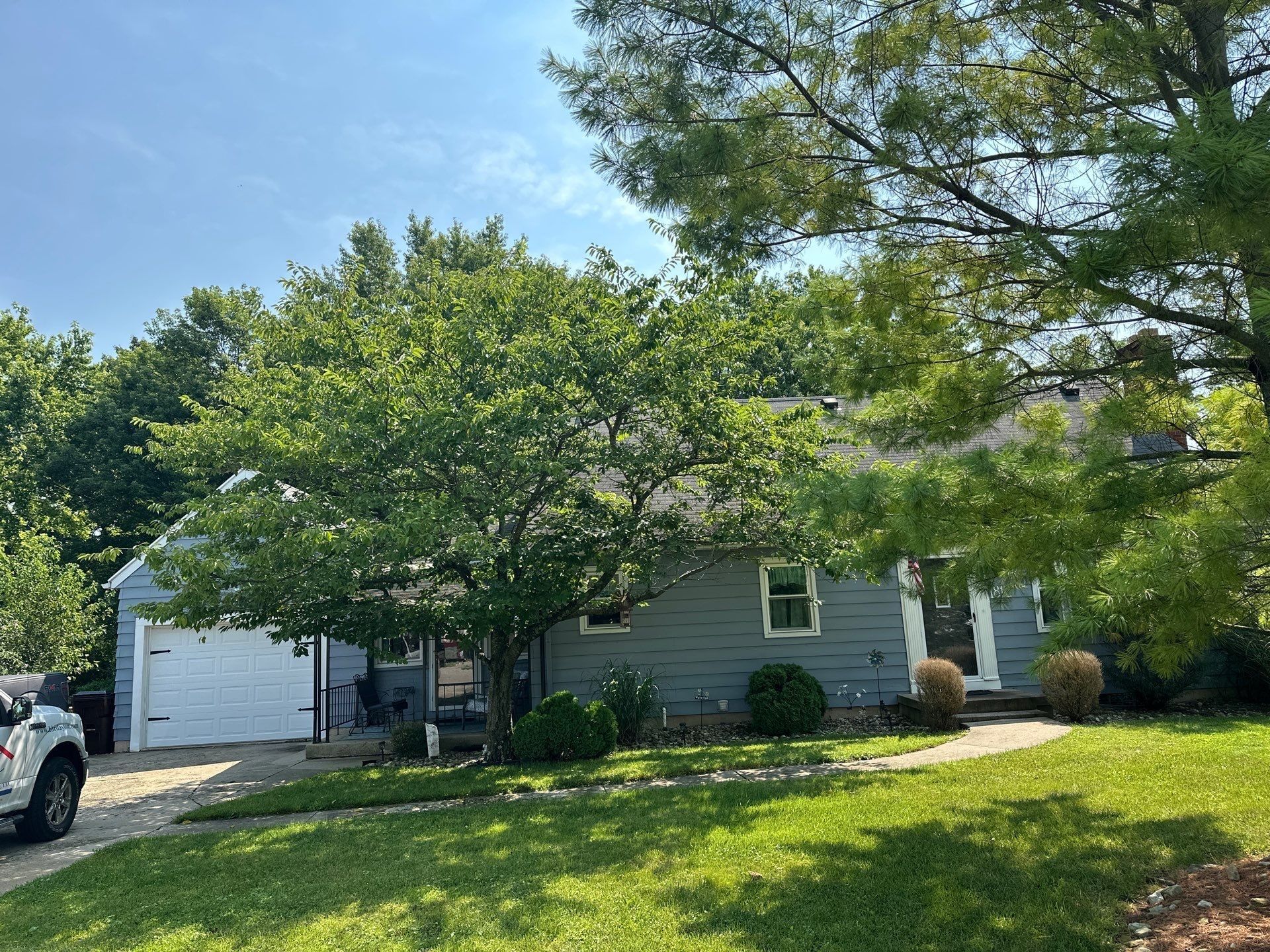 The front of the house and attached garage behind a flowering tree, Beavercreek, Ohio.