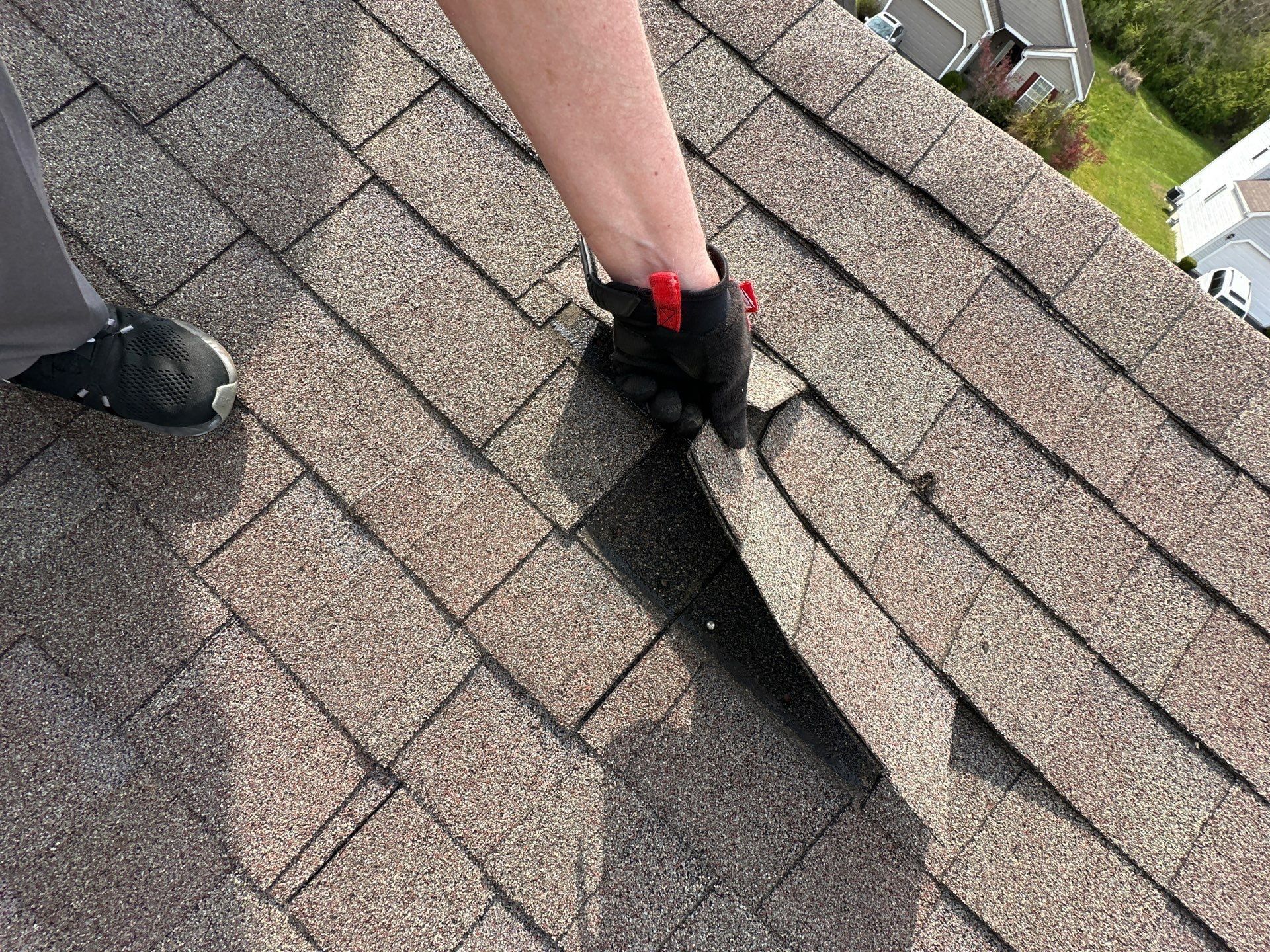 Gloved hand lifting a creased shingle