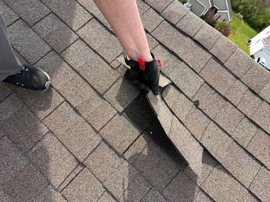 Gloved hand lifting a creased shingle