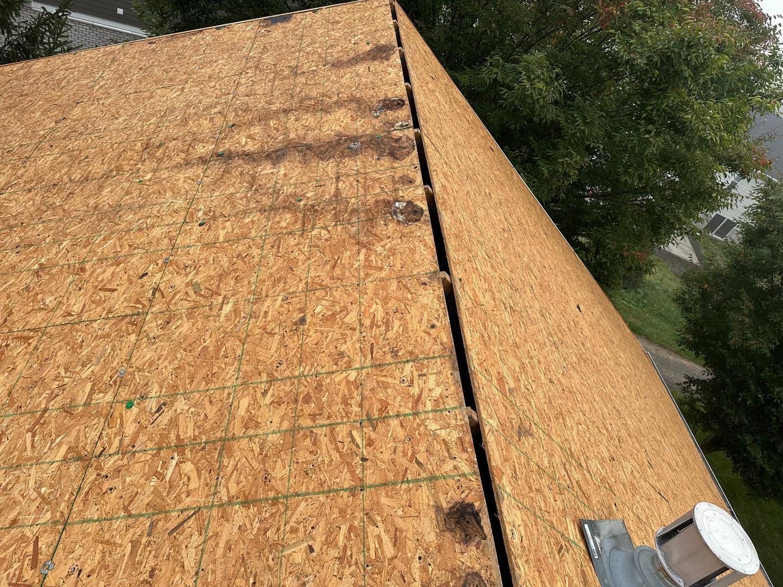 Bare deck after tear-off, with dark water stains along one seam, Beavercreek, Ohio.