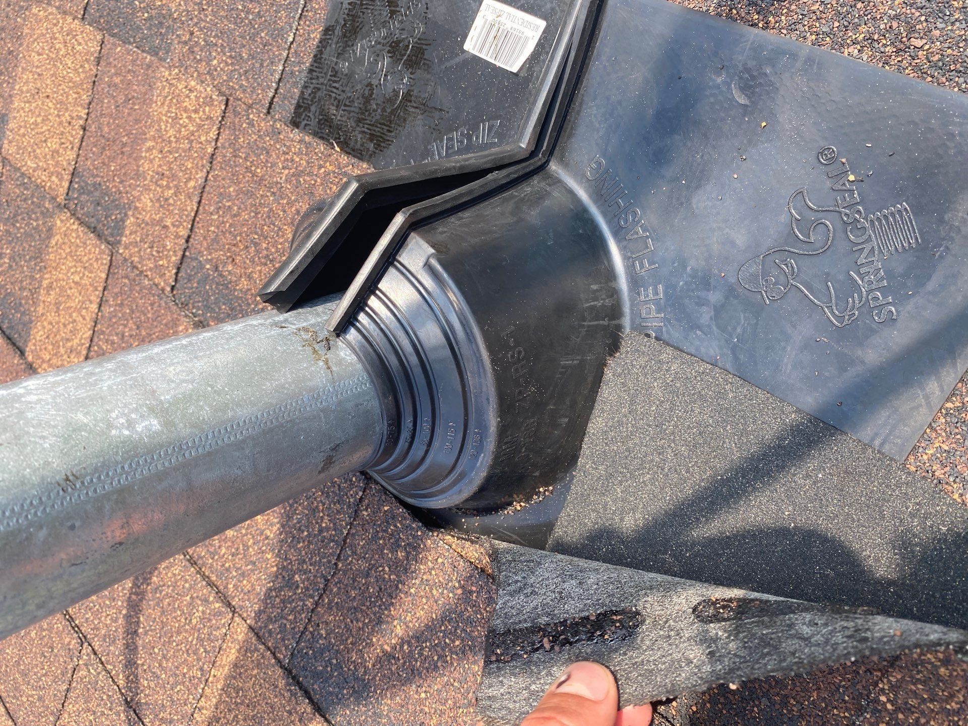 Rubber collar pipe boot sealed around a metal vent pipe in new shingles, Beavercreek, Ohio.