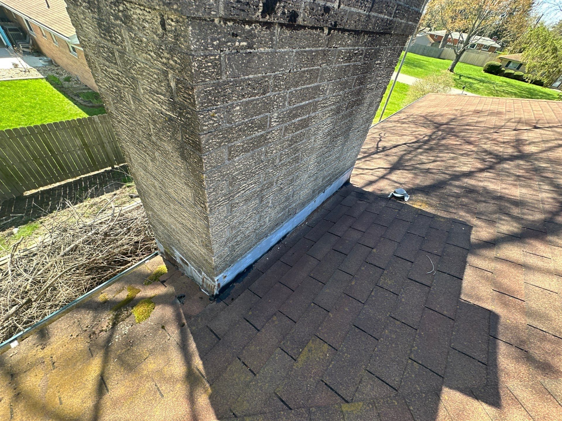 Stucco chimney base with aging metal flashing on the old roof, Beavercreek, Ohio.