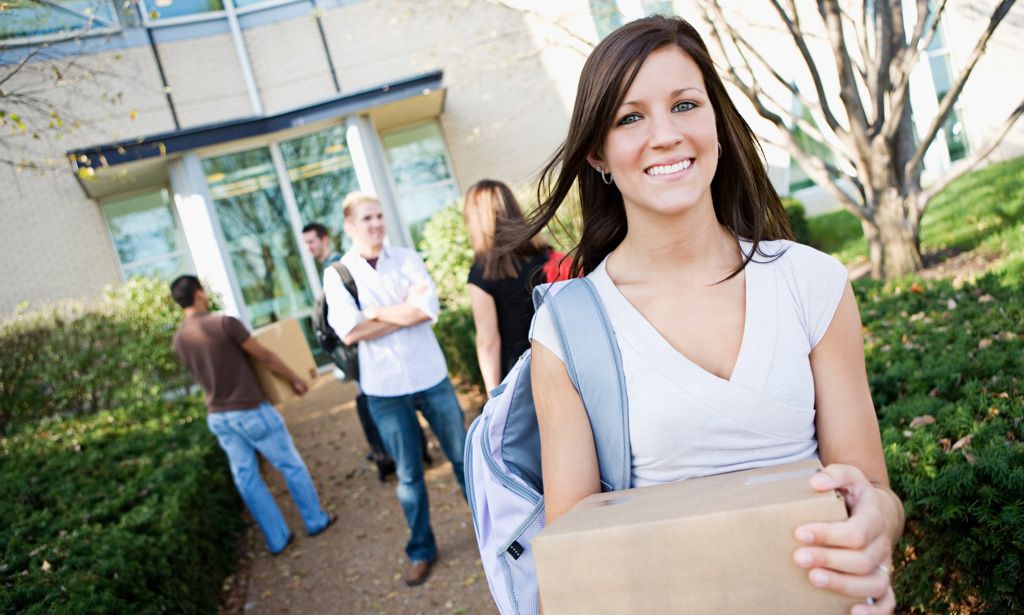 Woman smiling with friends while carrying a box