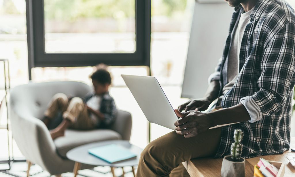 A father on a laptop with his son on a chair