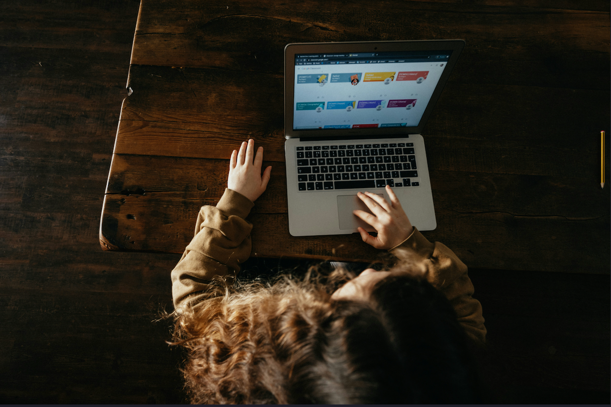 A high-angle view of a girl using a laptop on a white table.