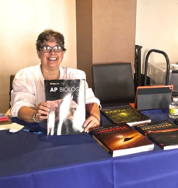 A woman sitting on a chair and posing with a book in her hand.
