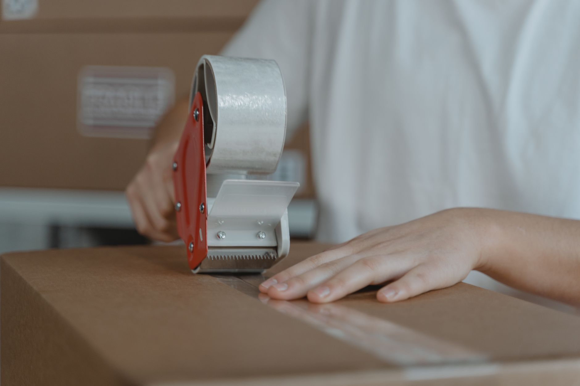 Hands sealing a brown cardboard box with packing tape, ready to ship souvenirs home from Japan