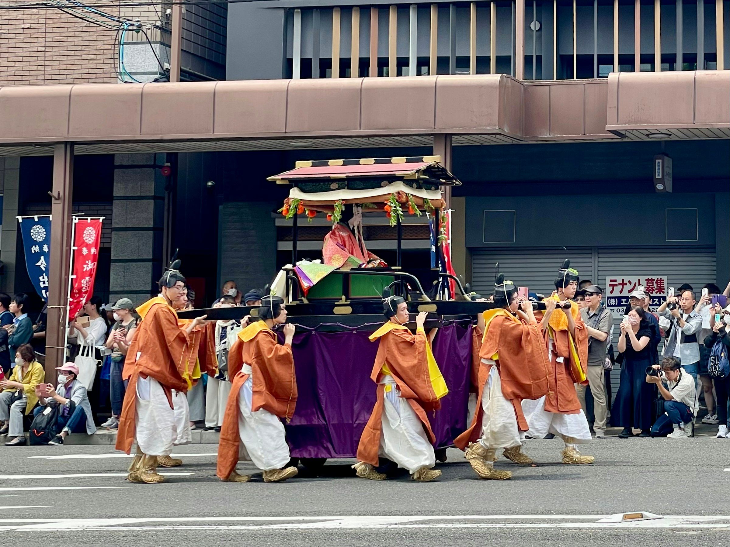 Crowd carrying a traditional festival float through a Kyoto street in summer