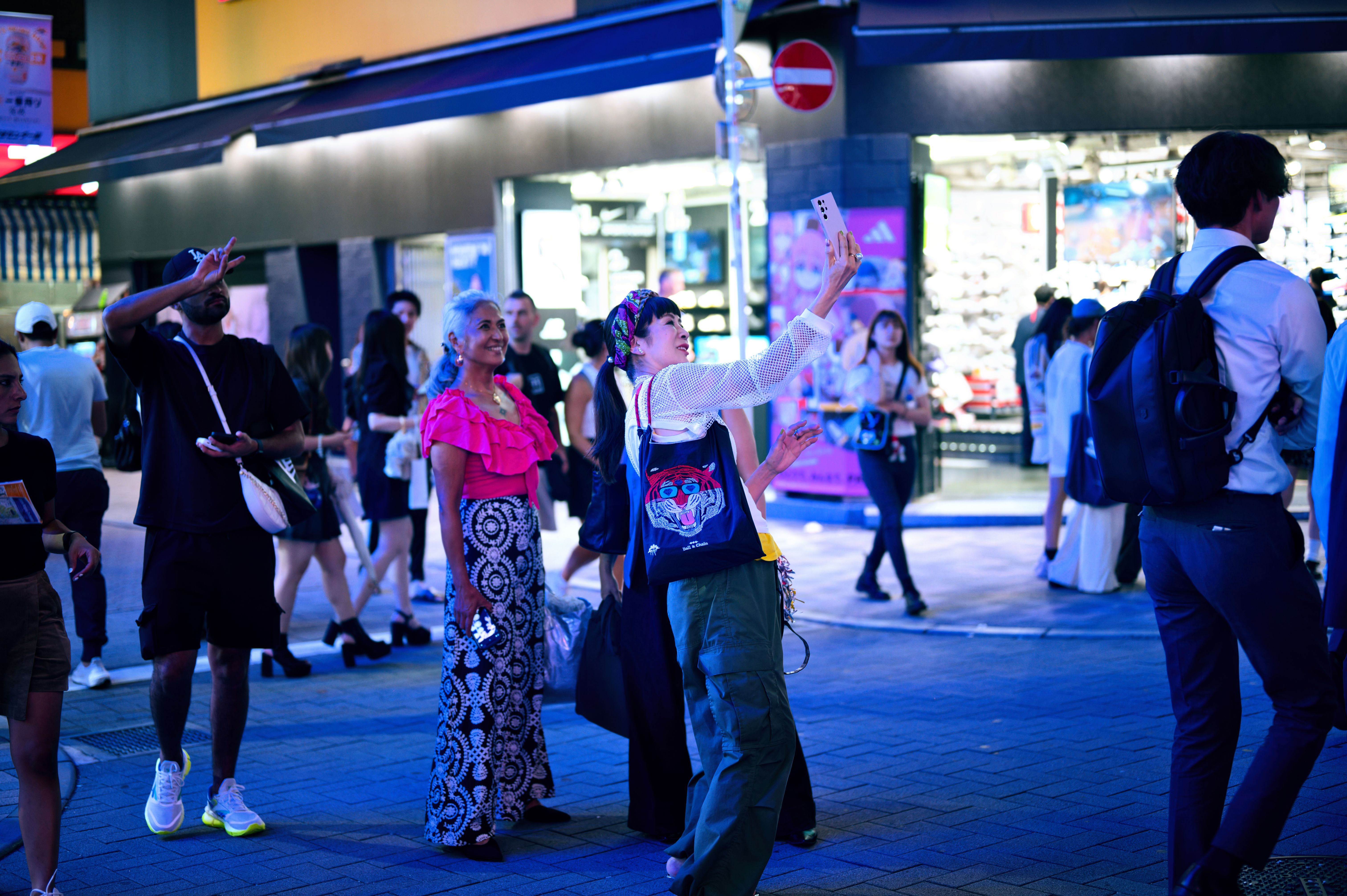 Person checking a smartphone on a busy neon-lit Tokyo street at night