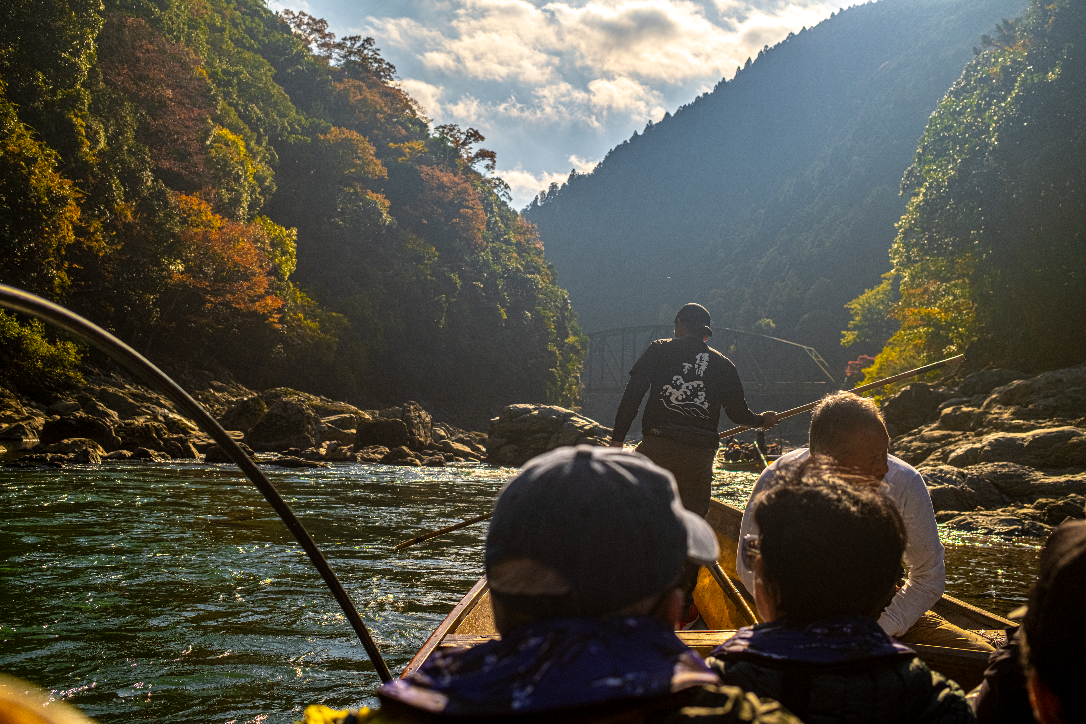A traditional wooden boat drifts down the Hozu Gorge below steep hillsides in full autumn colour near Kameoka, Kyoto
