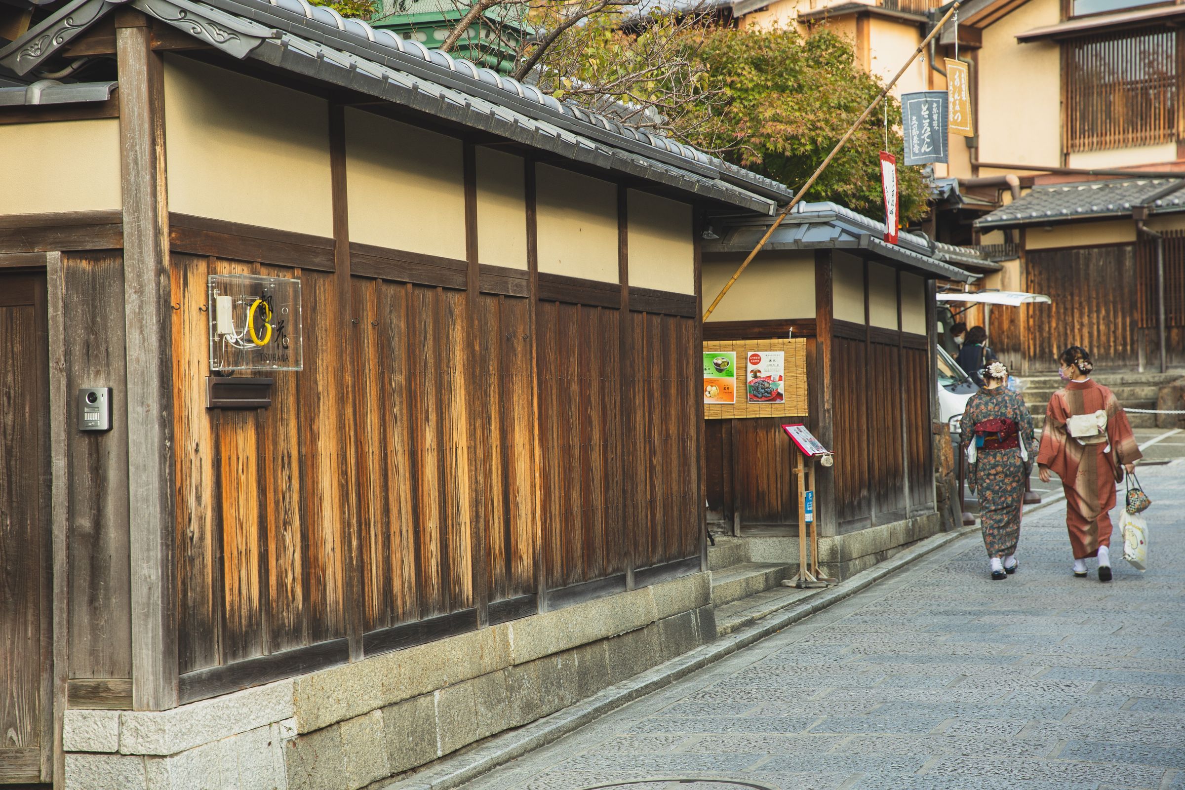 Women in kimono walking past traditional wooden houses on a Kyoto side street near Gion