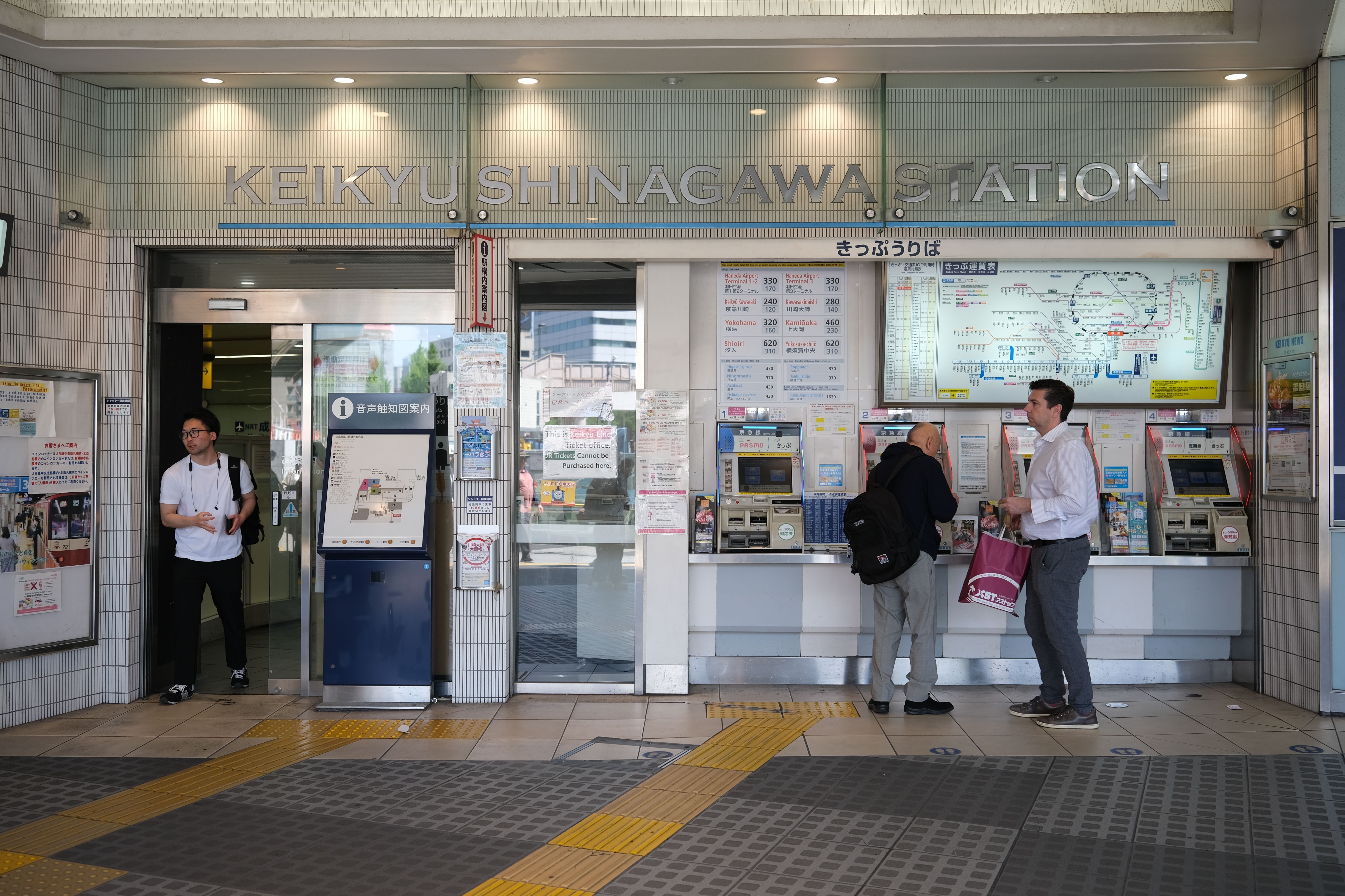 Travelers at IC card ticket machines inside a busy Tokyo train station, where Suica and Pasmo cards are bought and topped up.