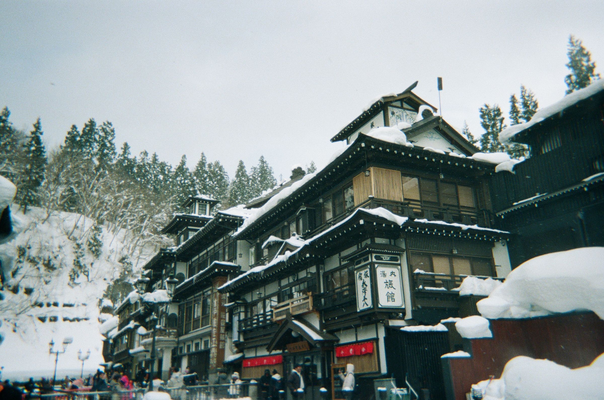 Snow piled on the roofs of Ginzan Onsen's wooden ryokan on a grey winter day in Yamagata