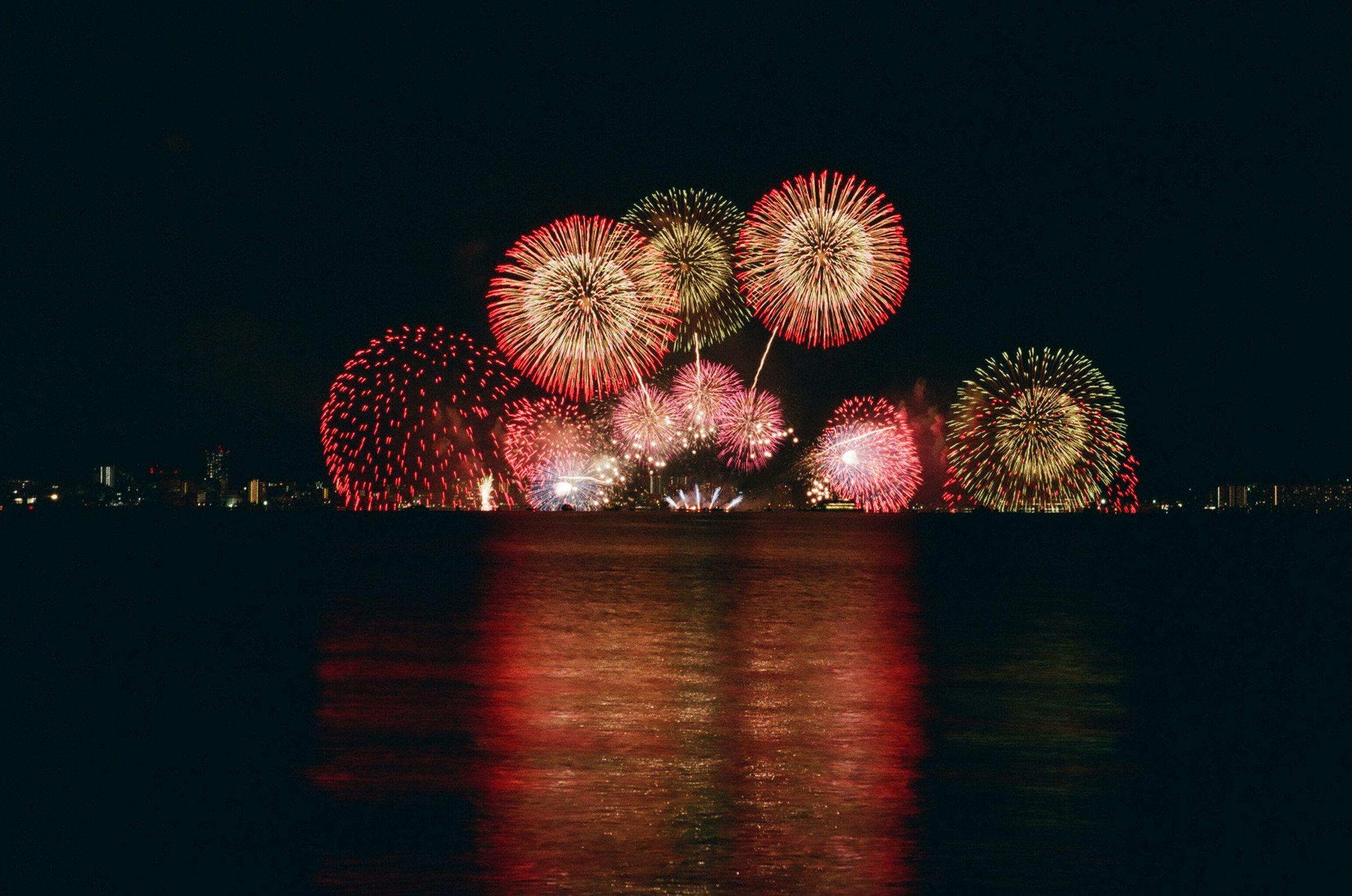 Summer fireworks bursting over water at a Japanese hanabi festival