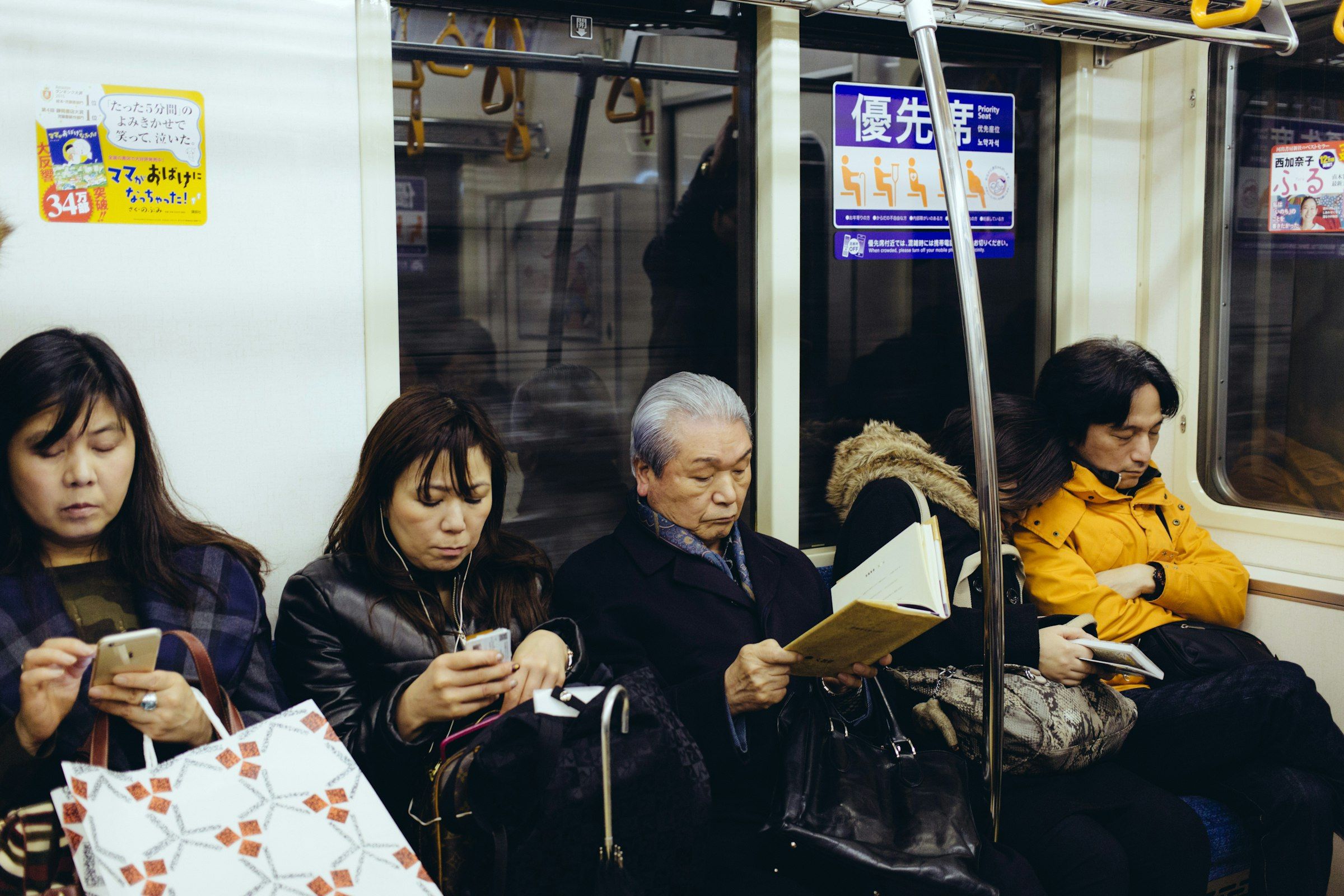 Passengers on a Tokyo metro train, several using their smartphones