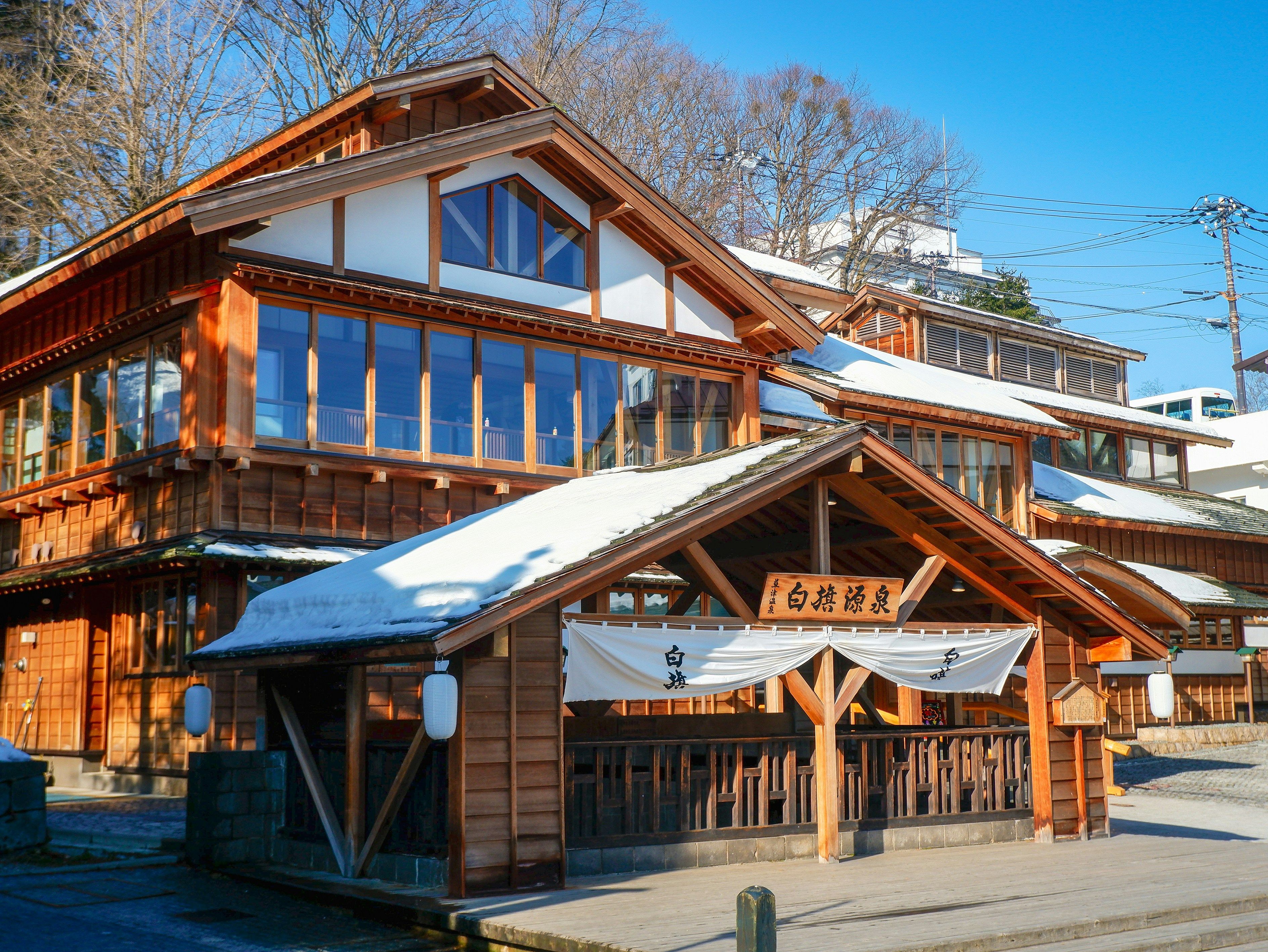 Snow on the wooden bathhouse roofs beside the Yubatake hot-spring field in Kusatsu Onsen, Gunma