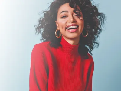 Smiling woman with braces in a red sweater