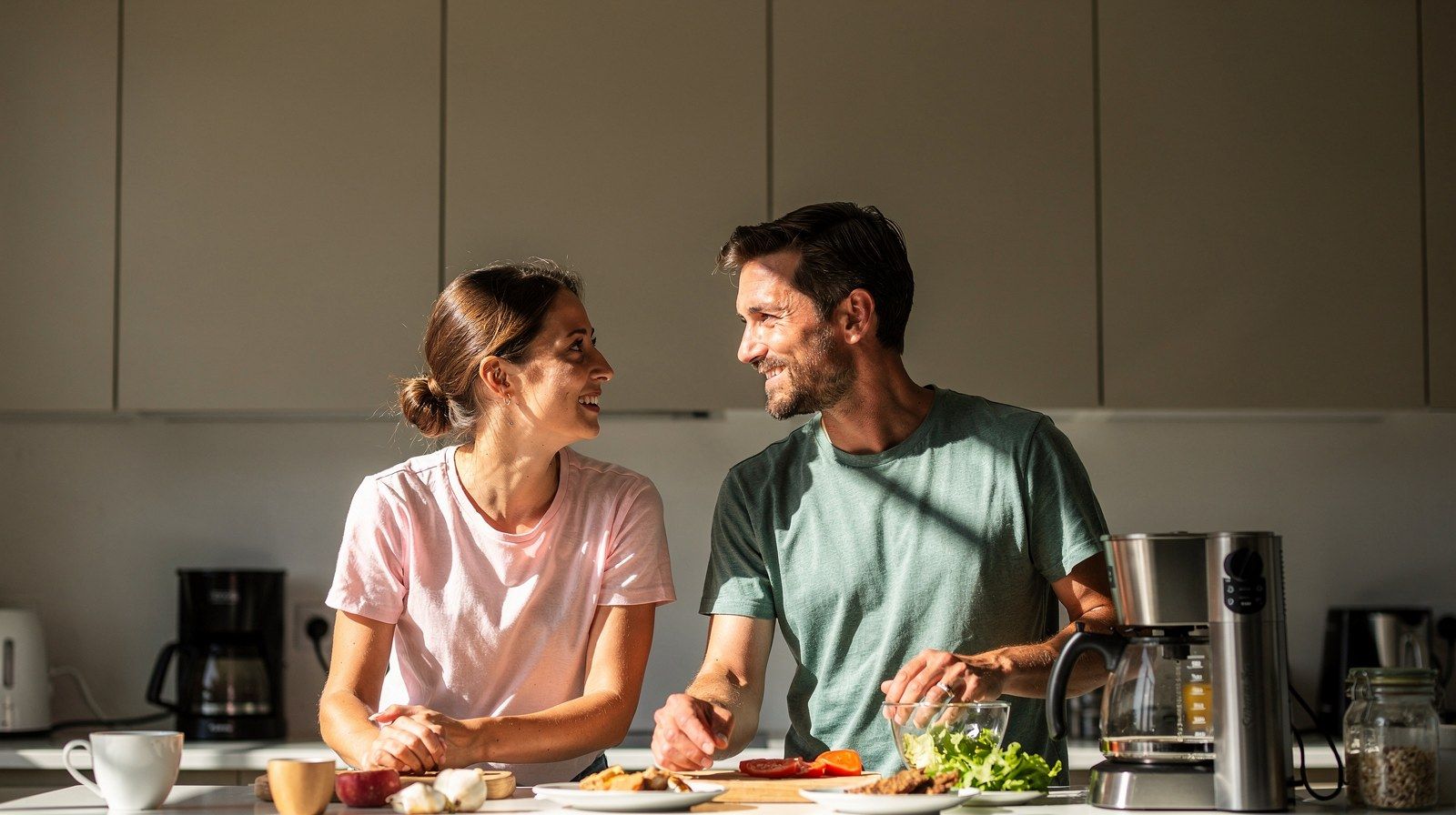 Due persone parlano in cucina, una si avvicina leggermente.