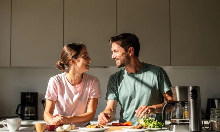 Due persone parlano in cucina, una si avvicina leggermente.
