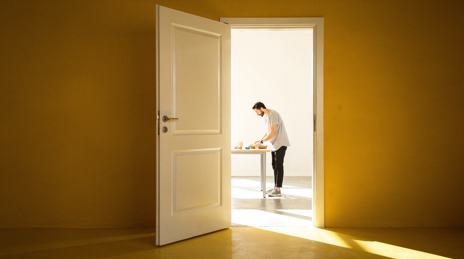Una porta socchiusa su una stanza luminosa e vuota.
