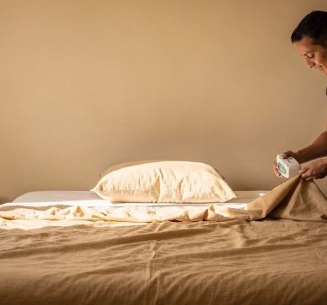 Un letto rifatto con un cuscino sistemato al centro, in una stanza vuota.