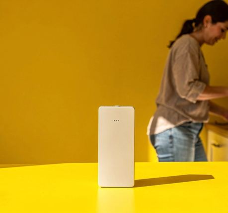 Un piccolo dispositivo elettronico su una superficie colorata, con un’ombra netta.