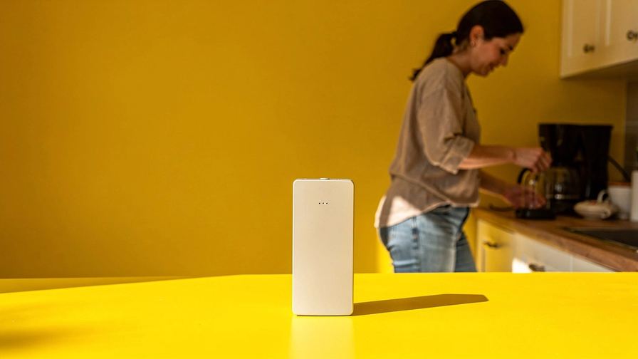 Un piccolo dispositivo elettronico su una superficie colorata, con un’ombra netta.