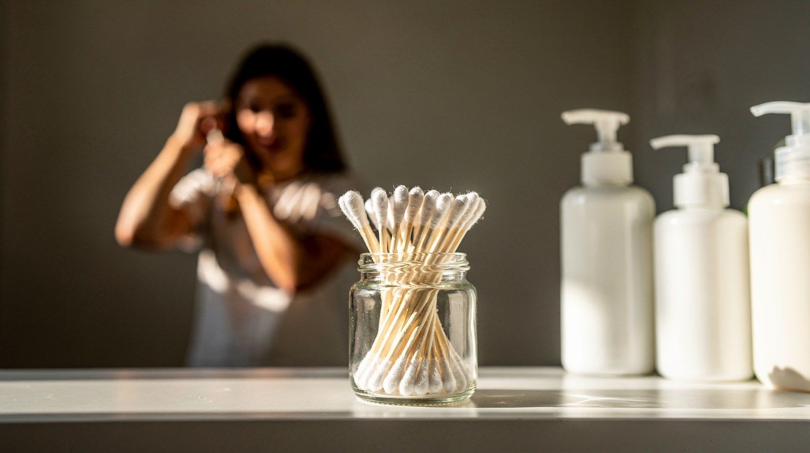 Cotton fioc in un piccolo barattolo di vetro su una mensola del bagno.