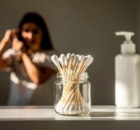 Cotton fioc in un piccolo barattolo di vetro su una mensola del bagno.