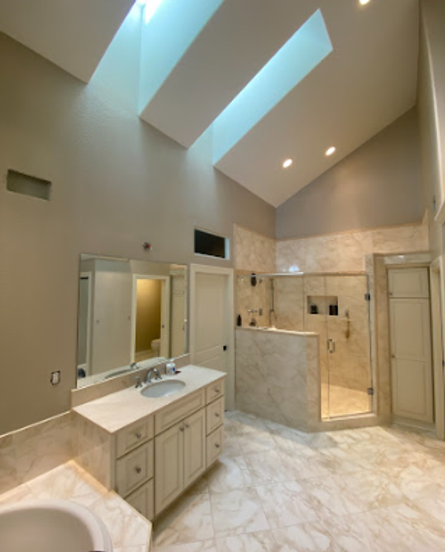 Spacious master bathroom with vaulted ceiling, neutral walls, and marble finishes