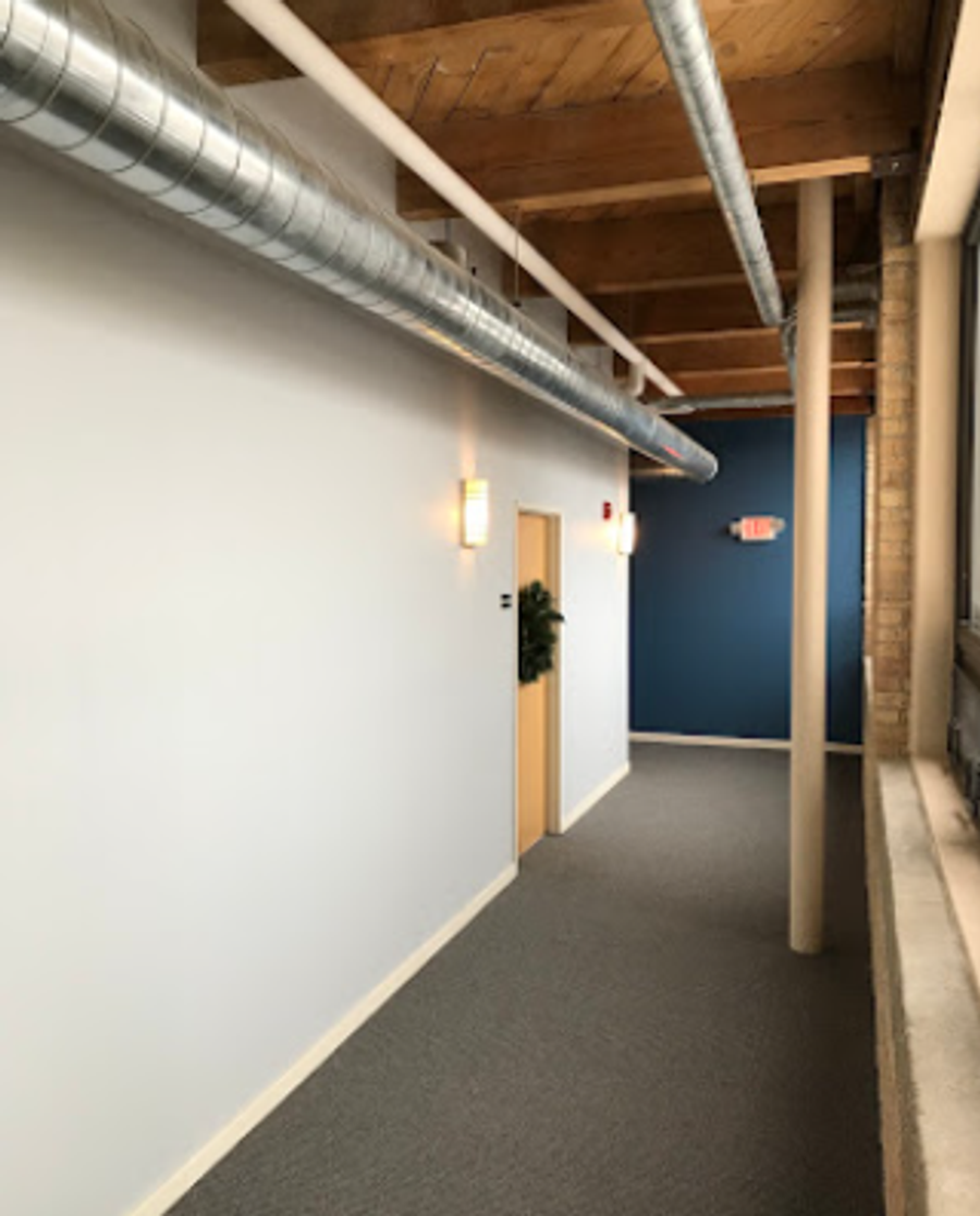Industrial loft hallway with exposed ductwork, wood ceiling, white walls, and a deep blue accent wall