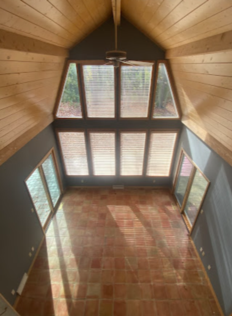 Vaulted sunroom with stained wood plank ceiling, grey accent walls, and floor-to-ceiling windows