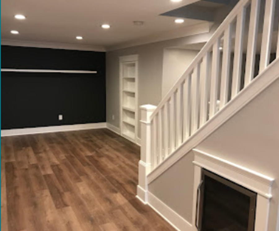Finished basement living area with crisp white trim, built-in shelving, and dark accent wall