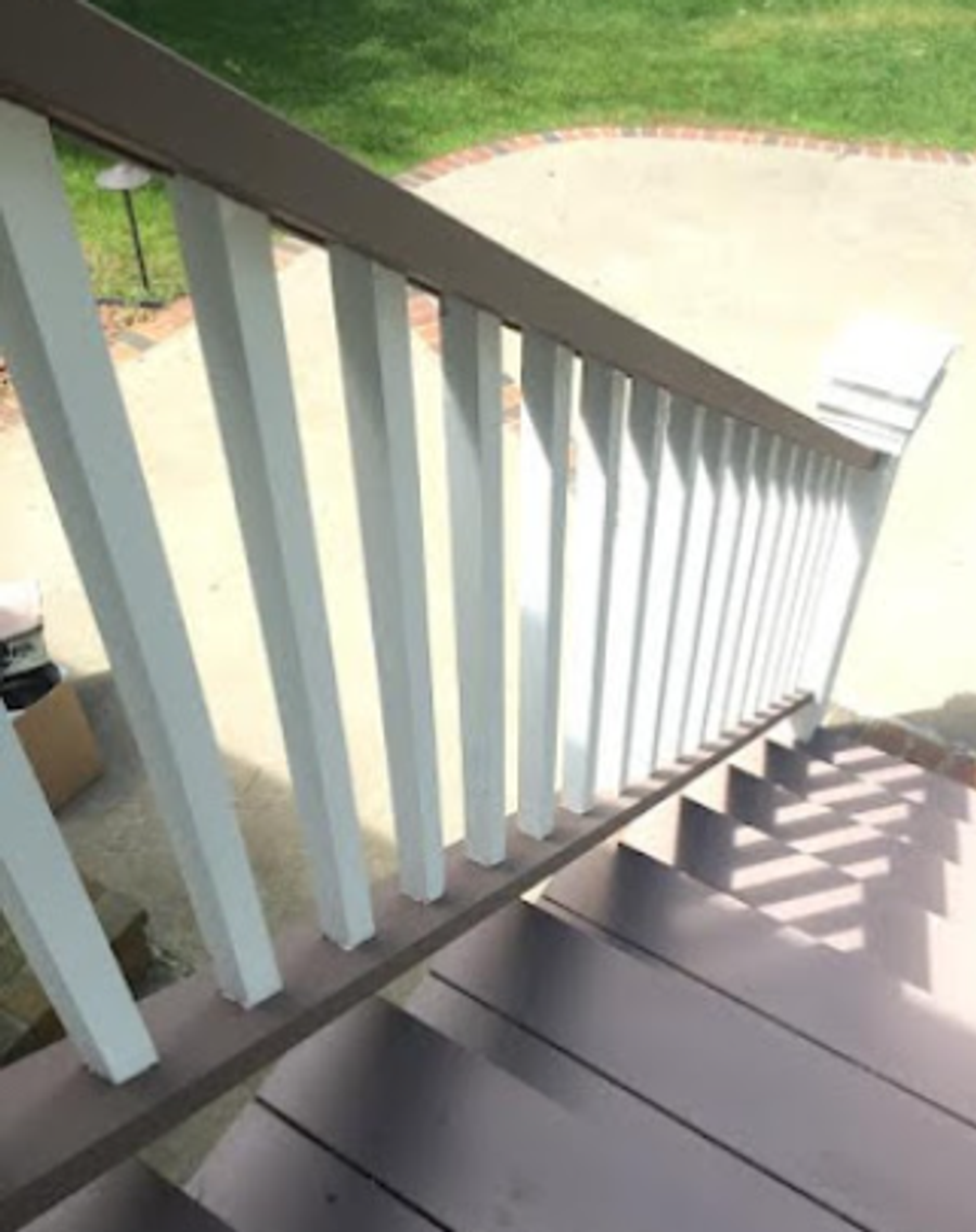 Freshly painted white exterior stair railing and grey-painted treads leading to a patio