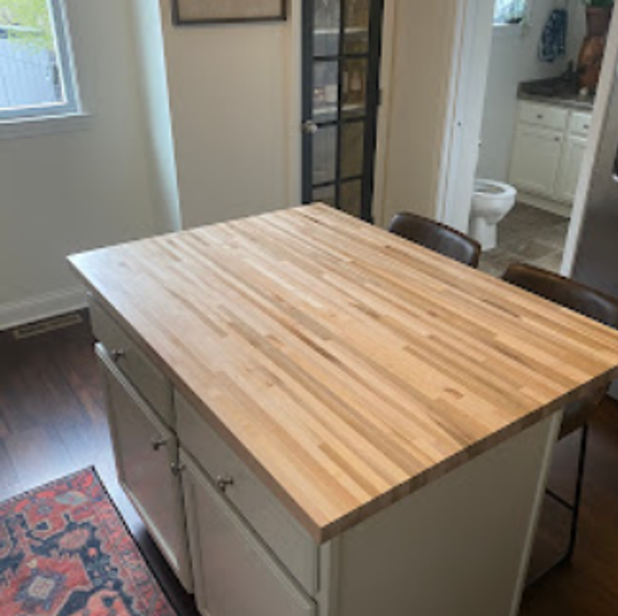 Bright kitchen with butcher-block island, white cabinetry, and natural wood floors