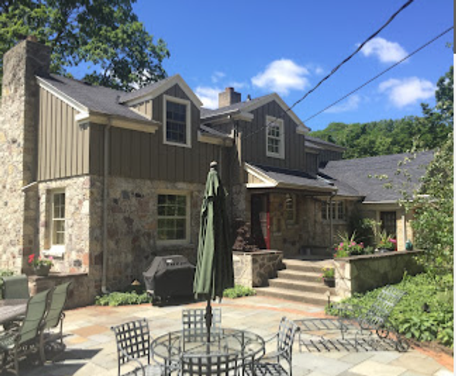 Stone-and-shingle exterior residence with freshly painted dark trim and patio