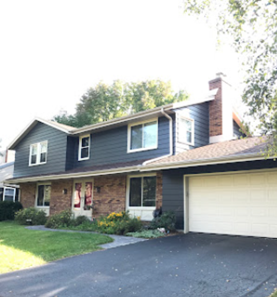 Two-story home exterior repainted with dark grey siding, brick lower level, and white garage door