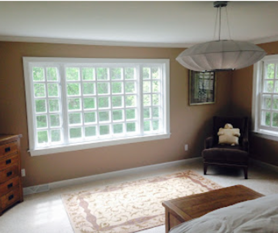 Sunlit bedroom with warm taupe walls, white window trim, and large picture window