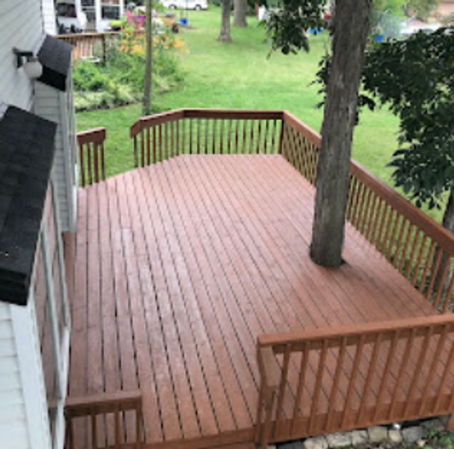Backyard cedar deck freshly stained in a warm reddish-brown tone overlooking a green lawn