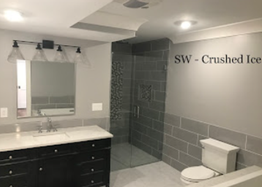 Modern bathroom remodel with grey tile, walk-in glass shower, and dark vanity