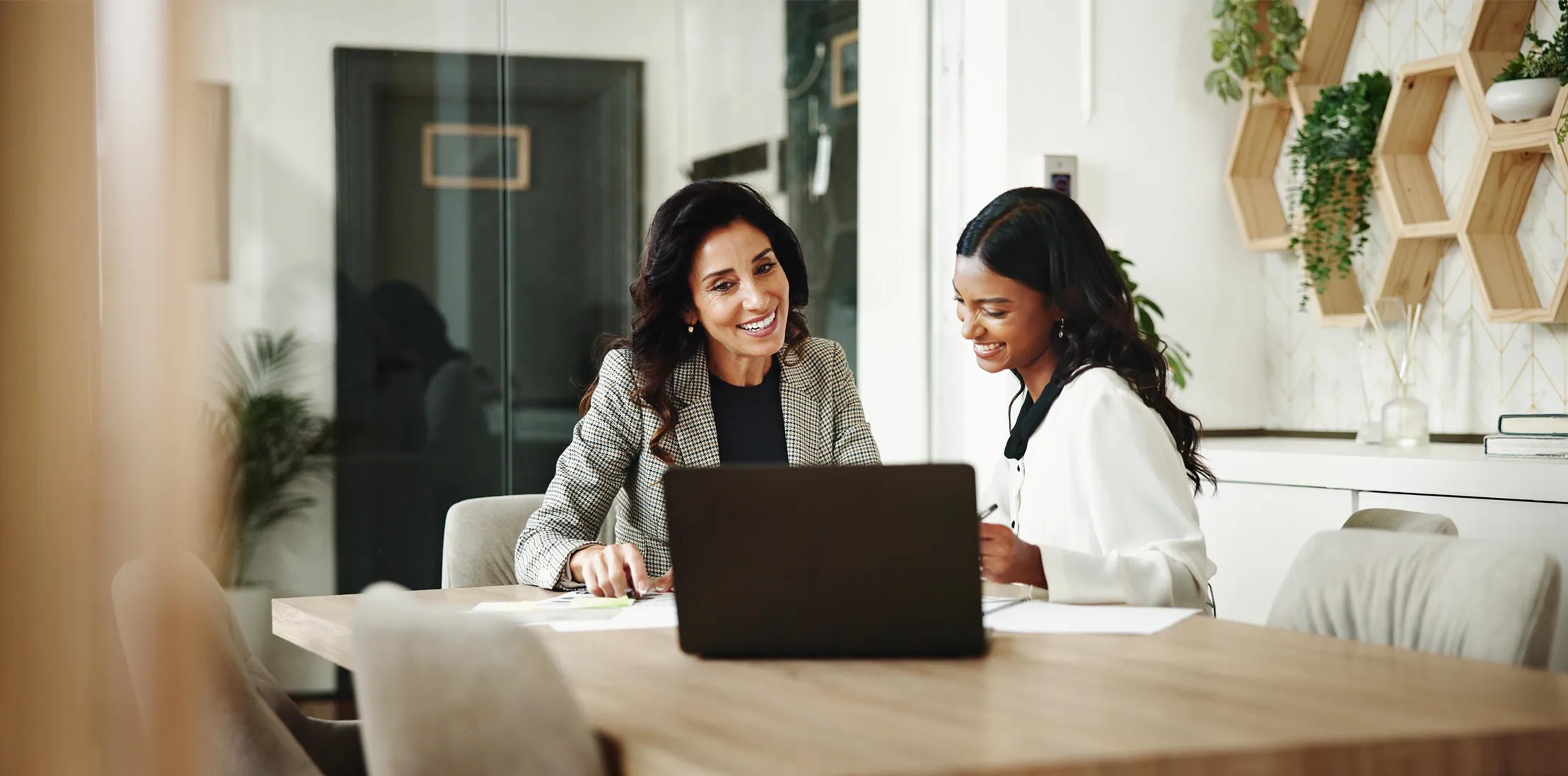 Two colleagues discussing information on a laptop