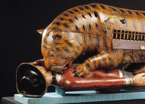A painted wooden tiger crouching over a European figure, with the organ exposed in its side.