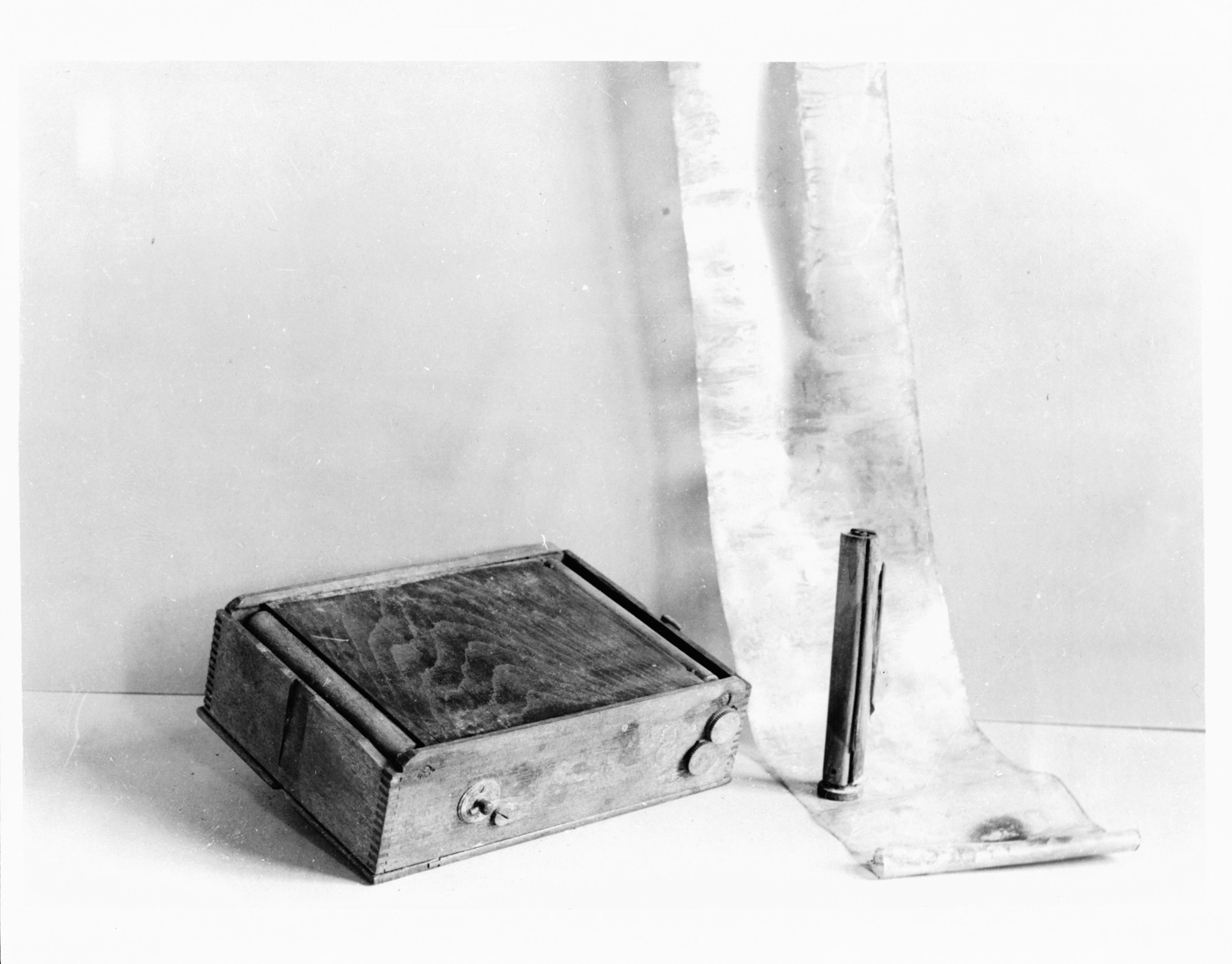 A wooden roll-film cassette beside its spool and a length of film