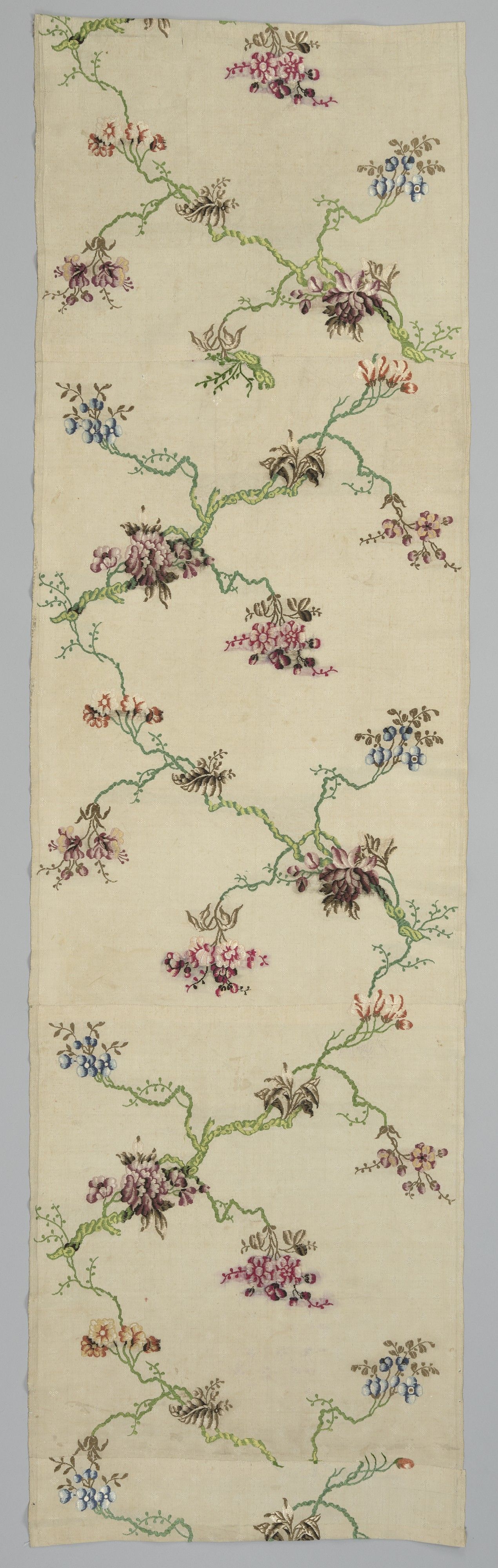 A narrow cream silk length with a meandering green branch, scattered pink and blue flower sprays and a repeating woven pattern